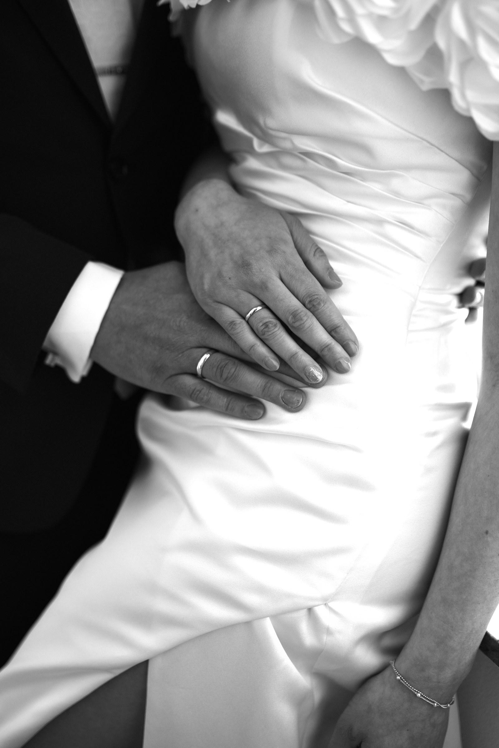 Hände mit Eheringen auf dem Brautkleid, Schwarzweiß