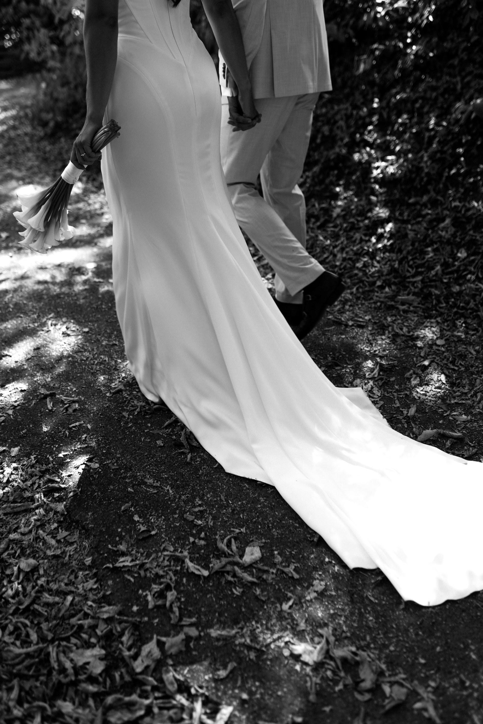 Die lange Schleppe des Brautkleids auf dem Waldweg, Schwarzweiß